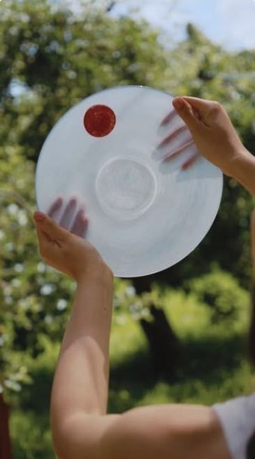 Hands holding a clear glass plate up to the sun